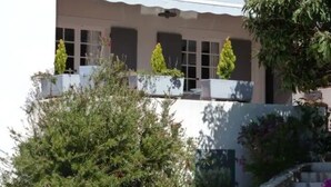 A building with a tiled roof, white walls, and a balcony with potted plants. - Magnifique Haut de Villa , Dans Impasse Calme, Piscine, 300m MER (Cavalaire-sur-Mer)