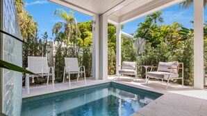A poolside area with white chairs and a clear blue pool.