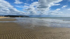 A beach with a clear sky and distant cliffs.