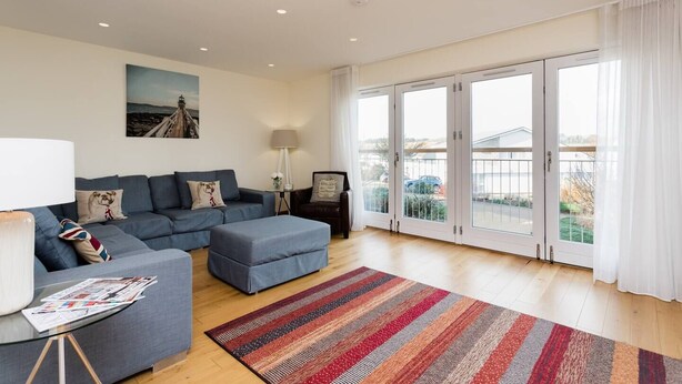 A modern living room with a sofa, ottoman, and a glass coffee table.