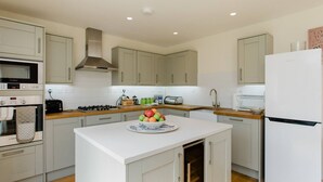 A modern kitchen with light-colored cabinets, a central island, a Bosch oven, a toaster, and a refrigerator.