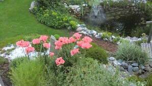 A garden with a pond, pink flowers, and a wooden fence. - Landhaus Dengg in Gerlos, "Almliebe" Apartment for 2 to 3 people (Gerlos)