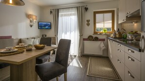 A modern kitchen with a dining area, featuring a wooden table, chairs, and a TV mounted on the wall. - Landhaus Dengg in Gerlos, "Almliebe" Apartment for 2 to 3 people (Gerlos)