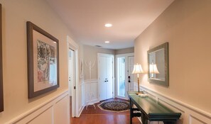 Stylish hallway leading to a room with a patterned rug and framed artworks.