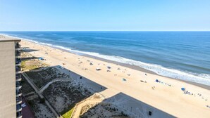 A beach with a clear view of the ocean, a sandy shore, and a building with balconies overlooking the beach. - English Towers-Beautiful Direct Ocean Views from this Remodeled Condo! (Ocean City)