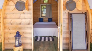 Eine Holzhütte mit Bett, Fenster und Tür.