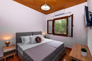 A bedroom with a bed, bedside tables, a TV, and a window with an open shutter. - Villa Avra - With Private Pool (Rethymno)