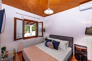 A bedroom with a bed, a window, a bedside table, and a lamp.
