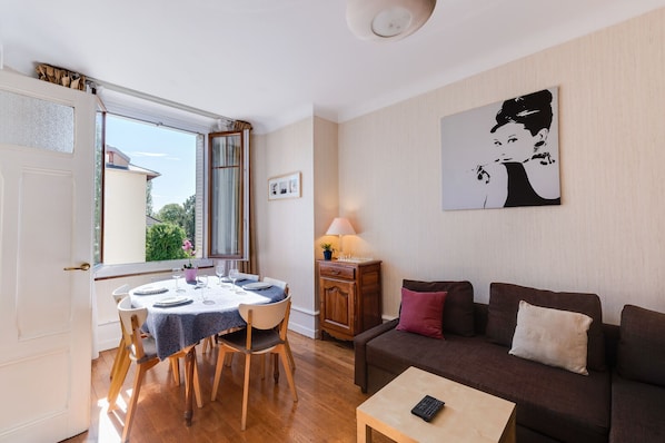 Ein Wohnzimmer mit Esstisch, Sofa und Lampe.