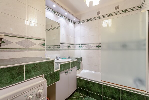 A bathroom with a sink, mirror, and bathtub.