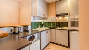 A modern kitchen with white cabinets, a stainless steel coffee maker, a microwave, and a dishwasher.