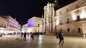 Una plaza histórica con arquitectura clásica, que incluye una iglesia destacada con un campanario.