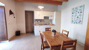 Una cocina pequeña con armarios blancos, una mesa de comedor de madera y un cartel de peces en la pared.