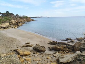 Una playa costera con terreno rocoso y una vista despejada del mar.