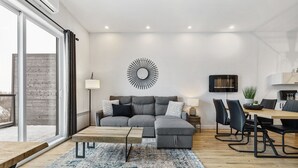 A modern living room with a sectional sofa, a coffee table, and a dining area with chairs and a table.