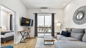 Een moderne woonkamer met een bank, een televisie en uitzicht op een besneeuwd landschap.
