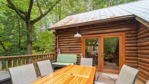 A wooden cabin with a deck, a table, and chairs. - 3BR cottage on the Toccoa River; fish from the yard, stargaze at the firepit! (Suches)