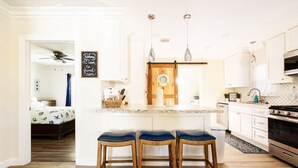Une cuisine moderne avec un îlot central, des tabourets en bois et des luminaires suspendus.