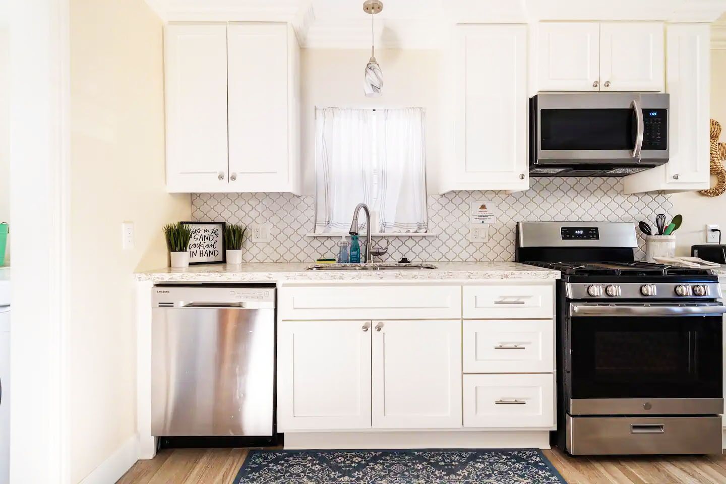 A modern kitchen with white cabinets, stainless steel appliances, and a patterned backsplash.