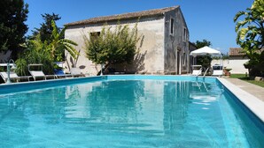 Une piscine avec des chaises longues et un bâtiment en arrière-plan.