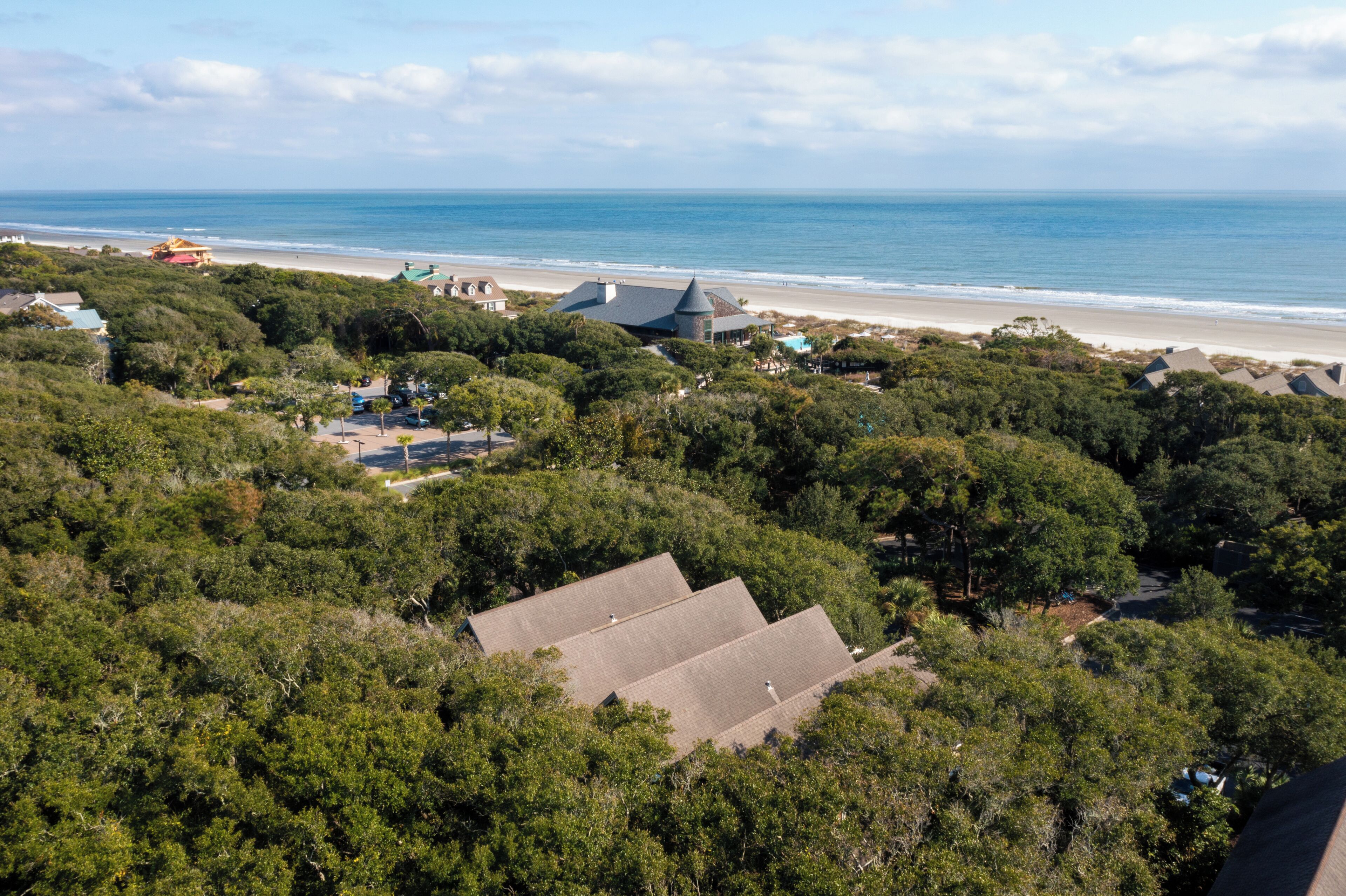 A coastal property with multiple buildings surrounded by dense greenery, overlooking a beach and the ocean.