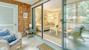 A room with a sliding glass door leading to a living area with a sofa, coffee table, and decorative items. - Across from beach, new bathroom reno! (Kiawah Island)