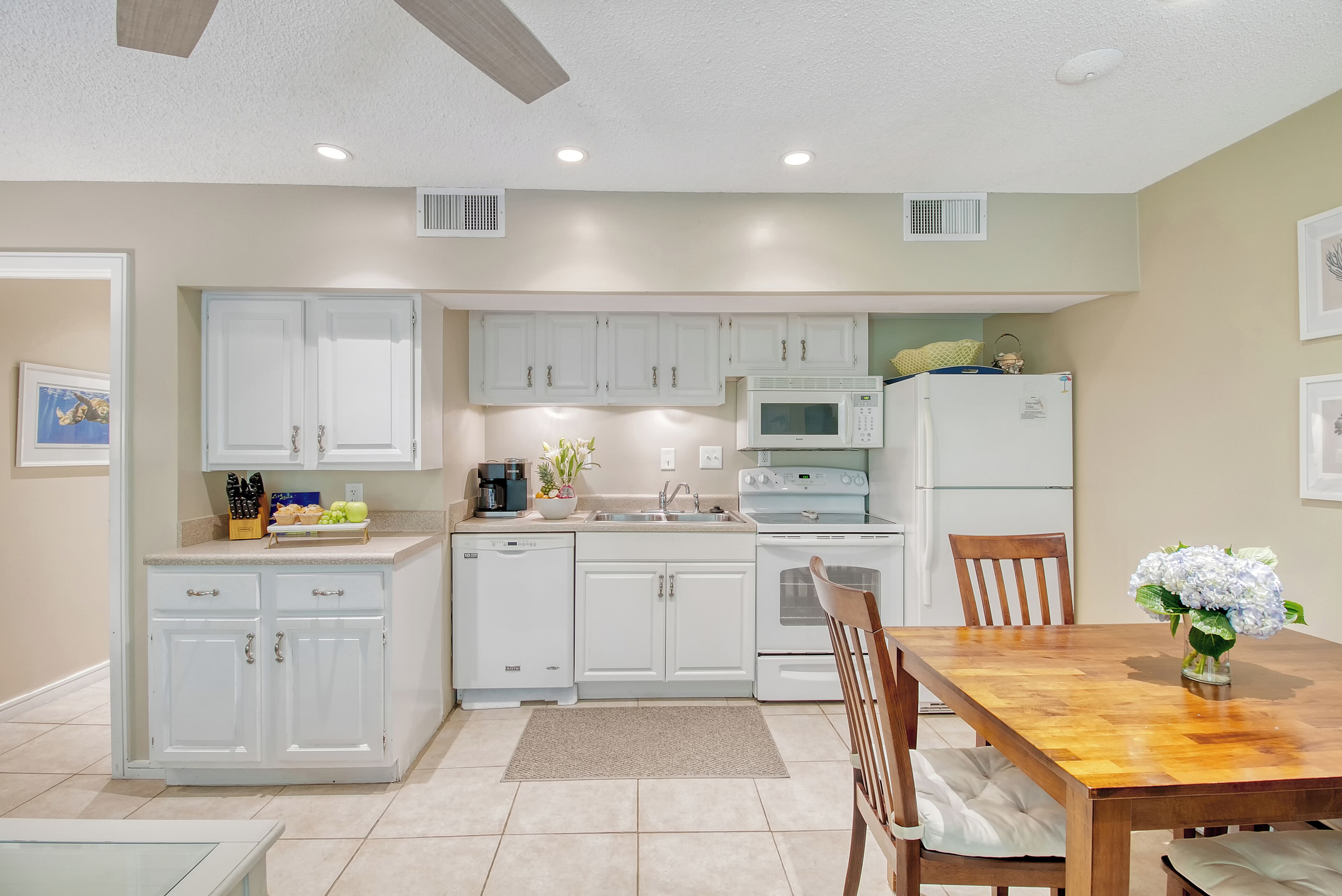 A modern kitchen with white cabinets, a microwave, stove, and a dining table with chairs.