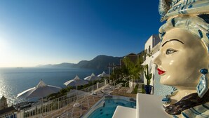 Ett poolområde med parasoller, en bubbelpool och utsikt över havet.