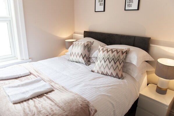 Cozy retreat with a large bed, bedside table, and lamp.