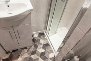 A bathroom with a sink, mirror, and shower area.