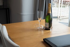Une table en bois sur laquelle se trouvent une bouteille de champagne et un verre vide.