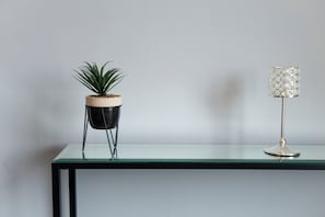 Taula de vidre amb una planta en test i una làmpada decorativa.