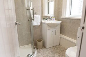 Bathroom features a glass-enclosed shower, pedestal sink, and toilet.