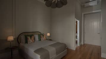 Une chambre à coucher comprenant un lit, des lampes de chevet, un ventilateur de plafond et une porte donnant sur une autre pièce.