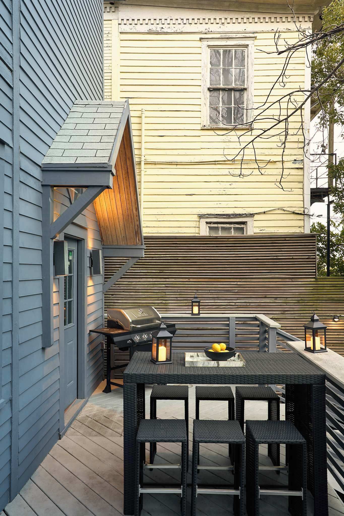 A patio with a grill, table, and chairs.