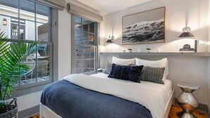 Un dormitorio moderno con una cama grande, vistas al exterior y una obra de arte colgada.