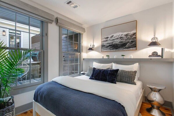 A modern bedroom with a large bed, a view of the outside, and a mounted artwork.