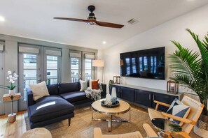 A modern living room with a dark sofa, round coffee table, and a ceiling fan.