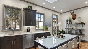 Una cocina moderna con armarios oscuros, un lavavajillas de acero inoxidable y una isla grande con sillas.