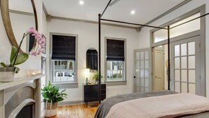 Un dormitorio con cama, cómoda, espejo y ventana con vista a la calle.