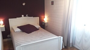 A neatly made bed with a white headboard, a purple pillow, and two bedside lamps.