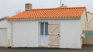 A small building with a tiled roof, a white exterior, and a wooden door.