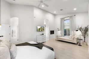 A modern bedroom with a bed, a sofa, a TV, and a window with curtains. - NEW|Private Waterpark Estate | Lazy River & Grotto (Scottsdale)