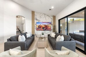 Ein modernes Wohnzimmer mit zwei grauen Sofas, einem Couchtisch und einem großen Gemälde einer Schluchtenlandschaft.