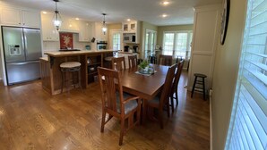 A spacious kitchen with wooden cabinets, a stainless steel refrigerator, and a dining area with a wooden table and chairs. - Private home on the bank of the White River (Flippin)