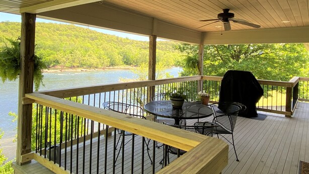 A covered deck with a view of a river and forest. - Private home on the bank of the White River (Flippin)
