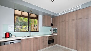Una cocina moderna con armarios de madera, horno empotrado y ventana con vistas a la vegetación.