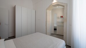 Quarto com cama, guarda-roupa e espelho.