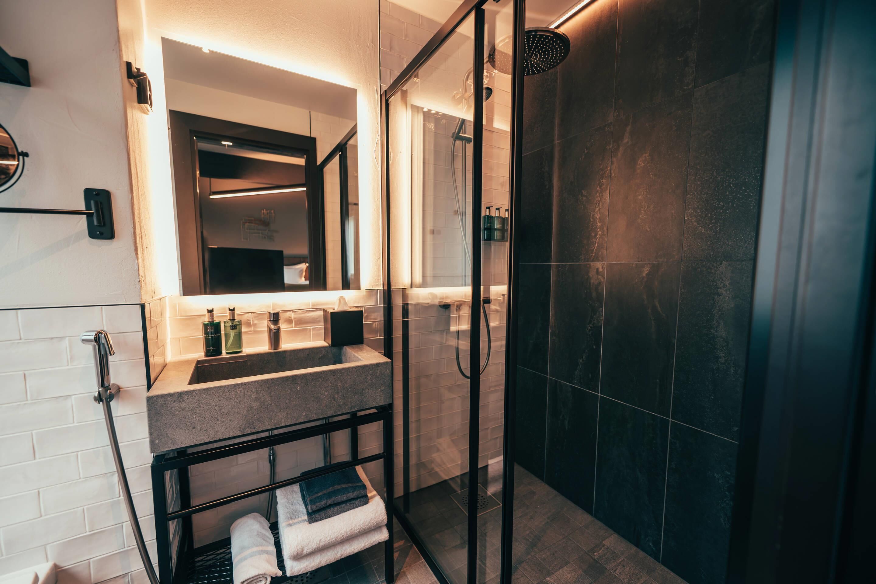 Un baño moderno con ducha de vidrio, tocador con espejo y un perchero para toallas.