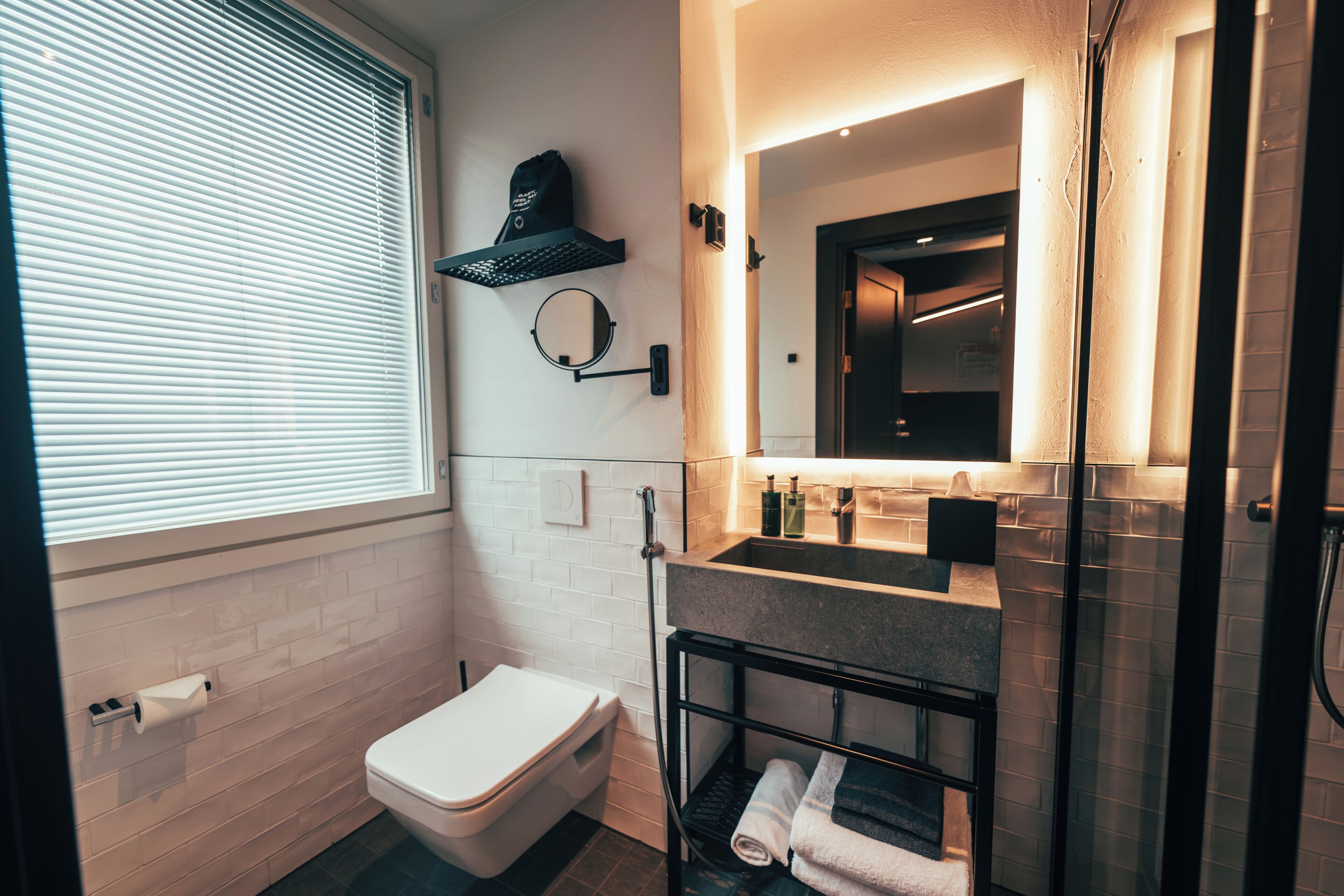 Un baño moderno con inodoro, lavamanos, espejo, toallero y ducha.